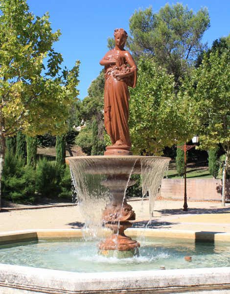 La fontaine de Saint-Clément-de-Rivière et sa statue, entourée de pins